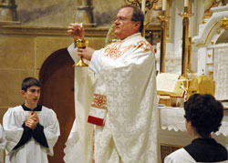 Priestly Fraternity of St. Peter Father Michael Magiera, associate pastor of Our Lady of the Most Holy Rosary Parish in Indianapolis, celebrates the traditional Latin Mass on Feb. 18 at the parish’s church. Altar server Simon Sheridan, a student at Lumen Christi School, kneels at left. (Photo by Sean Gallagher) 