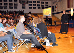 Father R. Tony Ricard, the Catholic chaplain for the New Orleans Saints, holds a carved stick from Senegal during his keynote address on the “Pursuit of Glory” on Nov. 7 at Bishop Chatard High School. (Photo by Mary Ann Wyand)