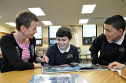 St. Philip Neri School teacher Tara DeRossett of Indianapolis helps sixth-grader Kevin Chaparro, center, and seventh-grader Sergio Sevilla read a book on Jan. 19 at the Indianapolis East Deanery grade school. The boys are from Mexico, and began classes at St. Philip Neri School in November. (Photo by Mary Ann Wyand)