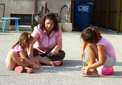 Cami Pritchett takes time from her duties as the director of Becky’s Place, a Catholic Charities homeless shelter for women and children in Bedford, to draw chalk art with two girls who are residents of the facility that opened this year. (Submitted photos by Corrina Cazares)