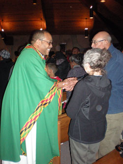 Divine Word Father Stephan Brown offers a sign of peace to Rhoda and Thomas Keough during the 10th annual St. Martin de Porres feast day Mass on Nov. 3 at St. Andrew the Apostle Church in Indianapolis. (Photos by Mike Krokos)