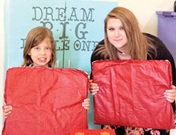 Cassandra Poynter, 17, right, and Children’s Liturgy of the Word participant Hannah Seitz, both of Nativity of Our Lord Jesus Christ Parish in Indianapolis, pose with mats and the cabinet Cassandra made to improve the children’s ministry in her parish. Cassandra’s efforts helped her to earn her the Girl Scout Gold Award. (Submitted photo)