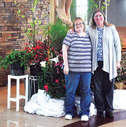 Jessica Pierce, left, and her sponsor Peggy Uhrick stand at the foot of the cross in the sanctuary of St. Malachy Church in Brownsburg, where Pierce was received into the full communion of the Church on April 15. (Photo by Natalie Hoefer)