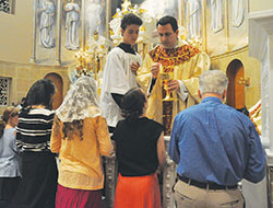 Bishop Steven J. Lopes, leader of the Houston-based Personal Ordinariate of the Chair of St. Peter, distributes Communion during a June 16 Mass at Our Lady of the Most Holy Rosary Church in Indianapolis. (Photo by Sean Gallagher)