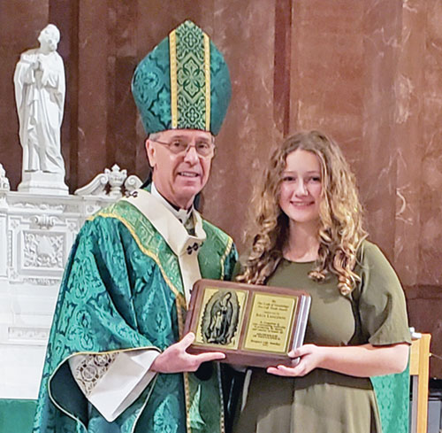 Julia Langdon smiles as she holds the Our Lady of Guadalupe Pro-Life Youth Award presented to her by Archbishop Charles C. Thompson during the Respect Life Mass at SS. Peter and Paul Cathedral in Indianapolis on Oct. 6. (Photo by Natalie Hoefer)