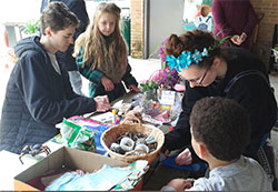 Saint Joseph High School senior Jack Thomas, left, and sophomore Emily Smith, right assist two young Earth Day participants in creating homemade wildflower seed packets and catnip toys. SECO volunteered to run the table for the Earth Day and Arbor Day activities on April 22 at Rum Village Park, South Bend.