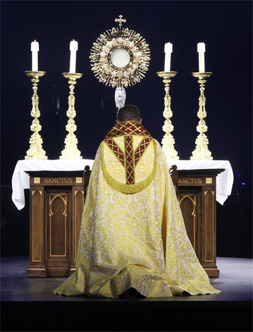 Bishop Andrew H. Cozzens of Crookston, Minn., chairman of the board of the National Eucharistic Congress, Inc., kneels in prayer before the monstrance during Eucharistic adoration at the opening revival night July 17, 2024, of the 10th National Eucharistic Congress at Lucas Oil Stadium in Indianapolis. (OSV News photo/Bob Roller)